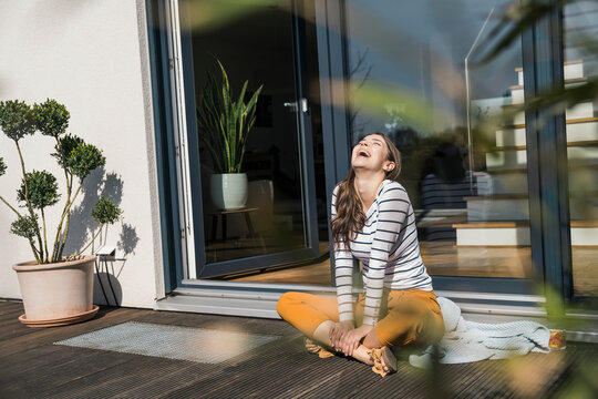 Woman enjoying leisure time on a terrace at home, smiling and relaxed.