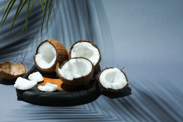 Fresh coconuts and shadow cast by tropical palm on grey background, closeup. Space for text