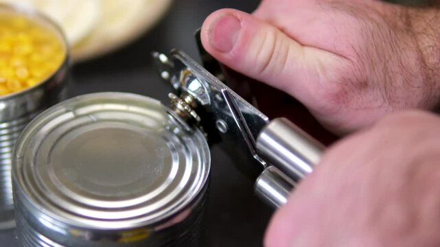 Hand opens metallic tin can of marinated sweet corn. Lifts the metal cover. Healthy vegetarian or vegan canned food concept. Top view. Vertical format. Close-up. High quality 4k footage