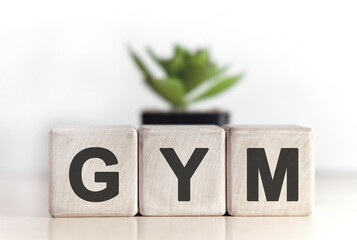 GYM- text on wooden cubes with In the background there is a green plant