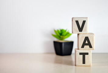 VAT - text on wooden vertical cubes with In the background there is a green plant