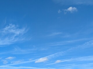 Blue Skies with wispy chemtrail aeroplane lines and fluffy white clouds