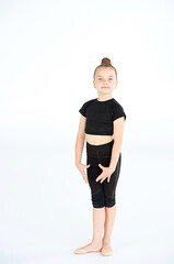 Portrait of junior gymnast in black sport swimsuit doing gymnastics exercises isolated over white...
