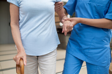 Doctor providing care for senior patient using cane for walking