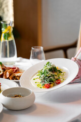 A plate of gourmet food garnished with fresh greens and cherry tomatoes, set on a white tablecloth...