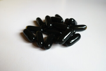 Handful of black softgel capsules of activated charcoal