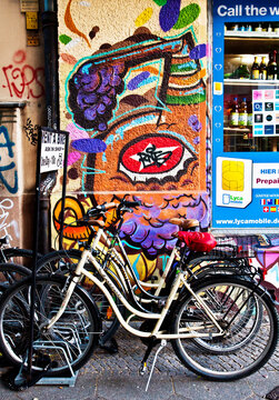 Berlin-Kreuzberg district:  bikes to rent with wall covered by graffiti behind