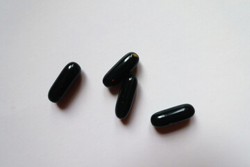 Four black softgel capsules of activated charcoal from above