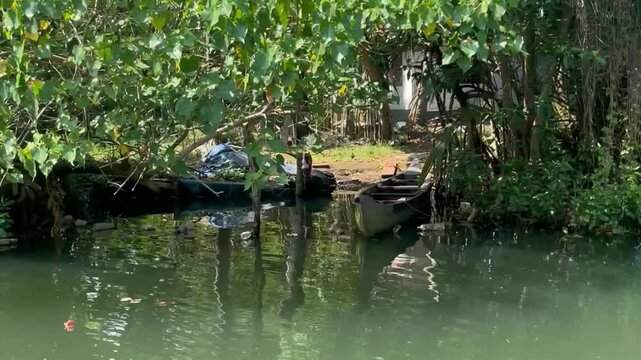 4K video of a lush green riverbank passing a parked boat and a private home
