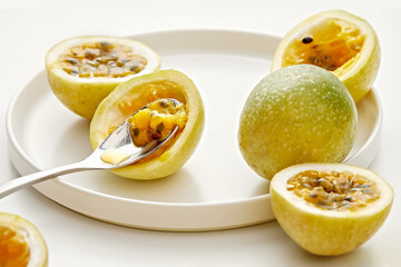 Close-up of fresh halved passion fruits on a plate with a spoon
