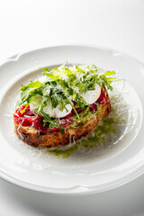 A delicious avocado toast topped with fresh tomatoes, mozzarella, and arugula, sprinkled with grated cheese, served on a white plate.