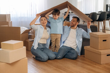 Playing with paper that is from the box. Family of husband, wife and son are moving into new house