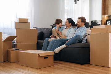 On the sofa, sitting and relaxing. Family of husband, wife and son are moving into new house