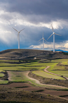 Landscape of Zaragoza with visible crop patterns and aligned wind turbines, capturing transition between traditional land use and clean energy