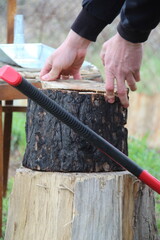 Men's hands place a burnt log to be chopped into firewood.