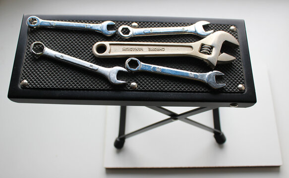 Adjustable wrench and variety spanners on a black tool table stand. Arrangement of tools at the handyman workplace
