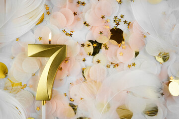 Seventh Birthday Celebration with Gold Candle and Confetti. Golden numeral seven birthday candle...