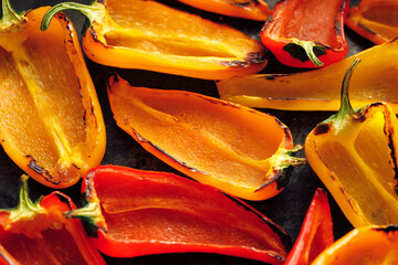 Grilled colorful peppers on a black background, focus on the middle