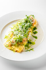 A vibrant plate featuring a gourmet dish with fresh greens, delicate pasta, and a sprinkle of grated cheese on a creamy white sauce, beautifully presented on a textured white plate.