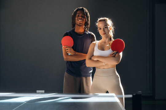 With arms crossed, standing together. Tennis game, man and woman are indoors - Powered by Adobe