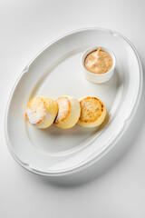 Delicious golden-brown cheese pancakes served on a white plate with a side of creamy peanut butter, perfect for breakfast or dessert