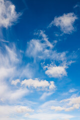 Bright blue sky with scattered white clouds, creating a peaceful and serene atmosphere. Light cirrus and cumulus clouds drift across a vibrant sky