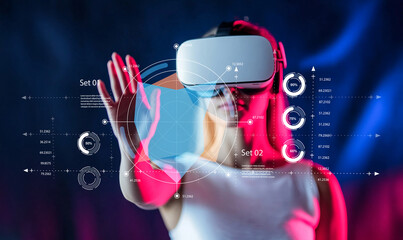 Young woman interacts with virtual reality technology while wearing a VR headset, exploring futuristic digital graphics, charts, and data visualizations © Luke