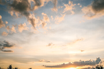 Colorful evening sky with dramatic scattered clouds glowing in the warm light of the setting sun,...
