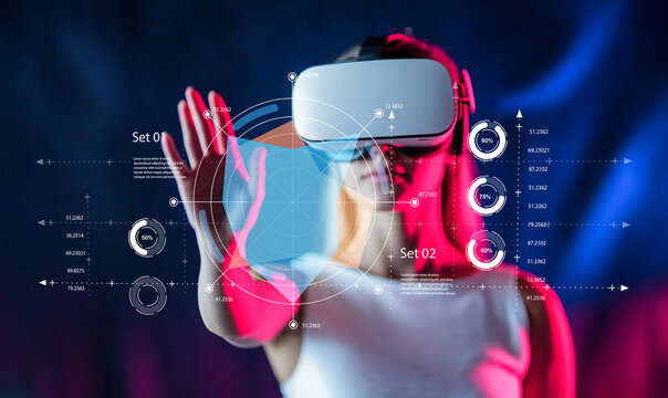Young woman interacts with virtual reality technology while wearing a VR headset, exploring futuristic digital graphics, charts, and data visualizations