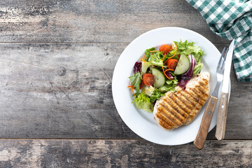 Healthy grilled chicken with salad on wooden table. Top view. Copy space