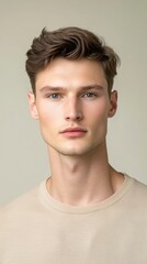 Obraz premium Portrait of a Young Man with Tousled Brown Hair Wearing a Beige T-Shirt
