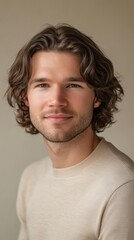 Fototapeta premium Portrait of a Handsome Young Man with Wavy Brown Hair Wearing a Cream-Colored Sweater