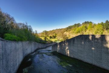 A beautiful, tranquil view of a narrow water passageway with lush, green walls leading to a...