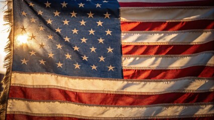 Fototapeta premium A weathered American flag with visible texture and light reflecting off its fabric, symbolizing patriotism and history.