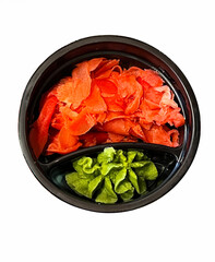 Black bowl with wasabi and pickled ginger on a white background. 