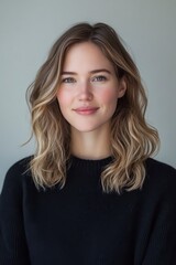 Fototapeta premium Portrait of a Young Woman with Wavy Blonde Hair, Wearing a Black Sweater