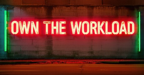 Glowing neon sign own workload in red and green tones thick glowing letters above cement wall with reflections and shadows