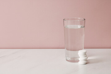 Effervescent tablets and glass of water are waiting on a marble table