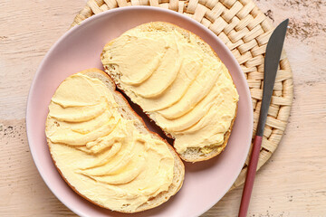Plate of tasty toasts with butter on white wooden background