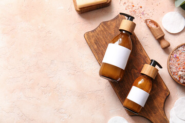 Bottles of shampoo, sea salt and cotton pads on beige background