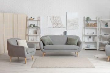 Interior of light living room with sofa, armchair and shelf units