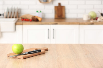 Cutting board with apple and knife on table in kitchen