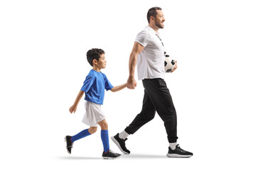 Full length profile shot of a boy holding hand with football coach and walking