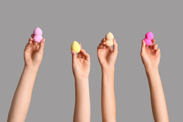 Female hands with different makeup sponges on grey background