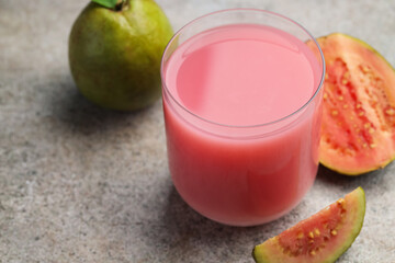 Refreshing guava juice and fresh fruits on grey table, closeup