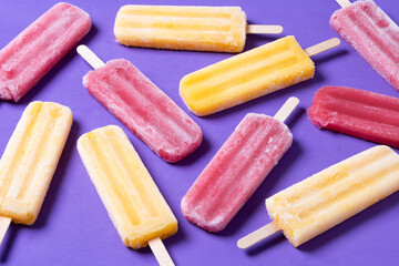 Yellow and red popsicles on purple background