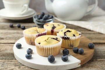 Delicious muffins with blueberries on wooden table, closeup