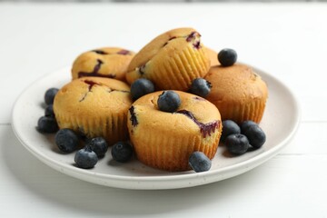 Delicious muffins with blueberries on white wooden table, closeup