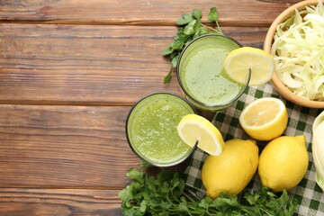 Healthy parsley drink in glasses, lemons and cabbage on wooden table, flat lay. Space for text
