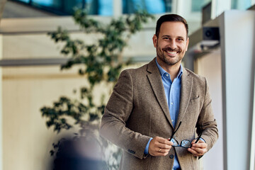 Smiling Professional Holding Glasses in a Modern Office Environment